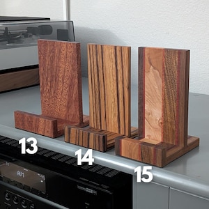 Handcrafted wooden now playing stand displayed as 3 separate stands sitting on a gray tabletop. Featuring Sapele, zebrawood, and walnut/maple Numbered 13-15