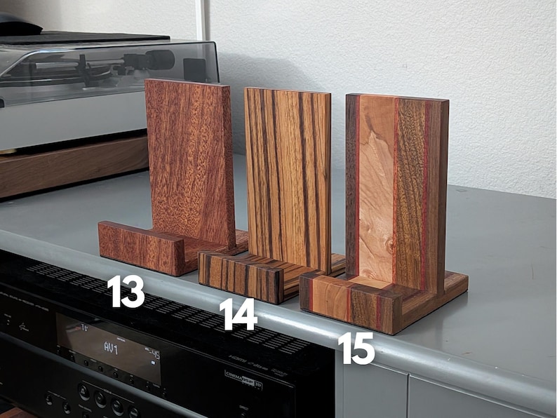 Handcrafted wooden now playing stand displayed as 3 separate stands sitting on a gray tabletop. Featuring Sapele, zebrawood, and walnut/maple Numbered 13-15