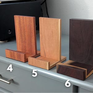 Handcrafted wooden now playing stand displayed as 3 separate stands sitting on a gray tabletop. Featuring mahogany, cherry, and katalox. Numbered 4-6