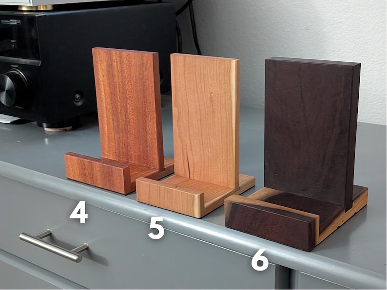 Handcrafted wooden now playing stand displayed as 3 separate stands sitting on a gray tabletop. Featuring mahogany, cherry, and katalox. Numbered 4-6
