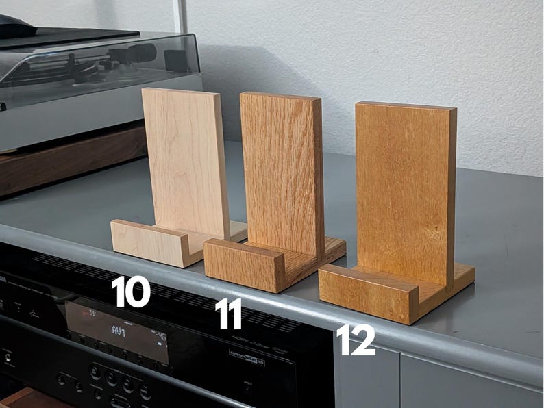 Handcrafted wooden now playing stand displayed as 3 separate stands siting on a gray tabletop. Featuring maple, oak, and movingui. Numbered 10-12