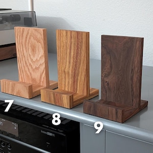 Handcrafted wooden now playing stand displayed as 3 separate stands siting on a gray tabletop. Featuring oak, canarywood, and walnut. Numbered 7-9