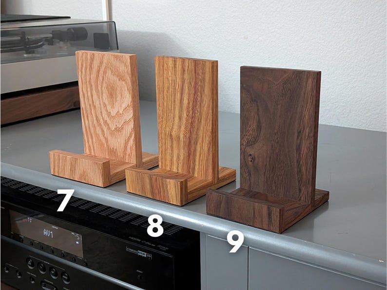 Handcrafted wooden now playing stand displayed as 3 separate stands siting on a gray tabletop. Featuring oak, canarywood, and walnut. Numbered 7-9