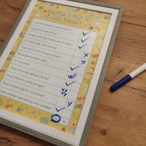 May include: A yellow and white checklist with the text "Should I stay in bed today?" and a series of questions with check boxes. The check boxes are marked with blue check marks and blue X's. The checklist is framed in a gray frame.