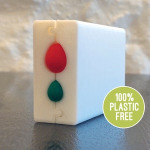 May include: A white, rectangular mould with two teardrop-shaped cavities. The top cavity is filled with red silicone and the bottom cavity is filled with green silicone. The mould is labelled "100% PLASTIC FREE".