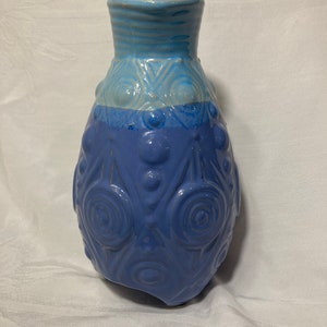 May include: A blue and white ceramic vase with a textured surface and a rounded shape.