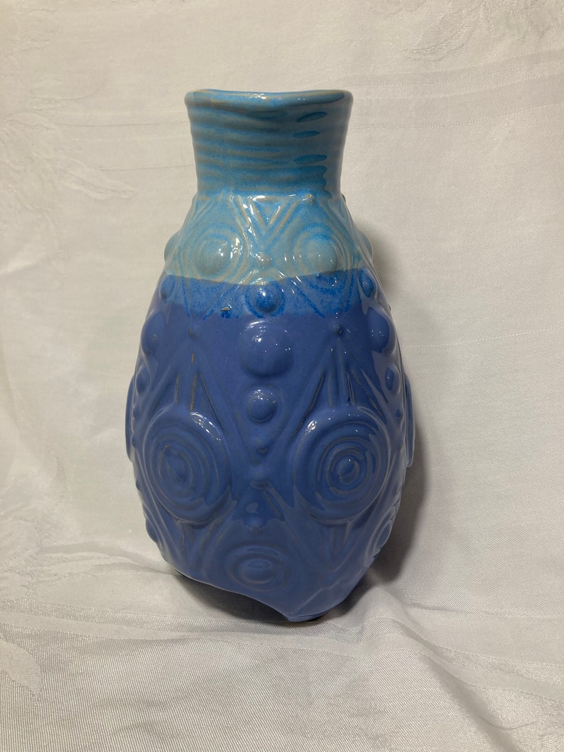 May include: A blue and white ceramic vase with a textured surface and a rounded shape.