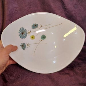 May include: White oval serving bowl with a floral design. The flowers are blue, green, and yellow.
