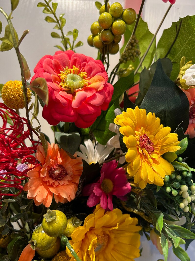 May include: A bouquet of artificial flowers in a variety of colors, including red, orange, yellow, pink, and white. The flowers are arranged in a vase and include daisies, zinnias, and other types of flowers.