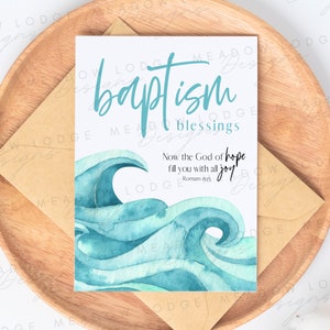 Op de afbeelding: Een witte kaart met blauwe aquarel golven en de tekst "baptism blessings" in zwarte cursieve letters. De kaart bevat ook de Bijbeltekst "Now the God of hope fill you with all joy." Romeinen 15:13.