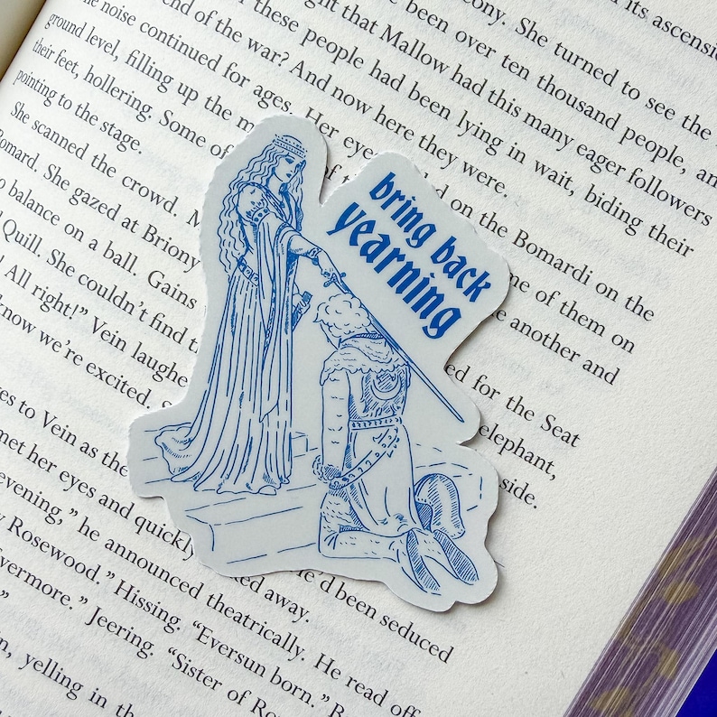 May include: A die-cut sticker featuring a blue and white illustration of a medieval scene. A woman in a long gown holds a sword over a kneeling figure. The sticker has the text "bring back yearning".