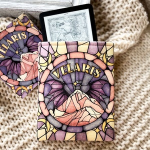 May include: A stained glass style e-reader cover with a purple, pink, and yellow design. The cover features a mountain range and the word "VELARIS" in gold lettering.