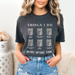 Może przedstawiać: Szary t-shirt z napisem "THINGS I DO" i grafiką sześciu ułożonych książek z r&oacute;żnym tekstem na każdej książce. Tekst na książkach brzmi: "READ BOOKS", "THINK ABOUT BOOKS", "ORGANIZE BOOKS", "TALK ABOUT BOOKS", "BUY BOOKS" i "RESEARCH BOOKS". Tekst "IN MY SPARE TIME" znajduje się pod grafiką.