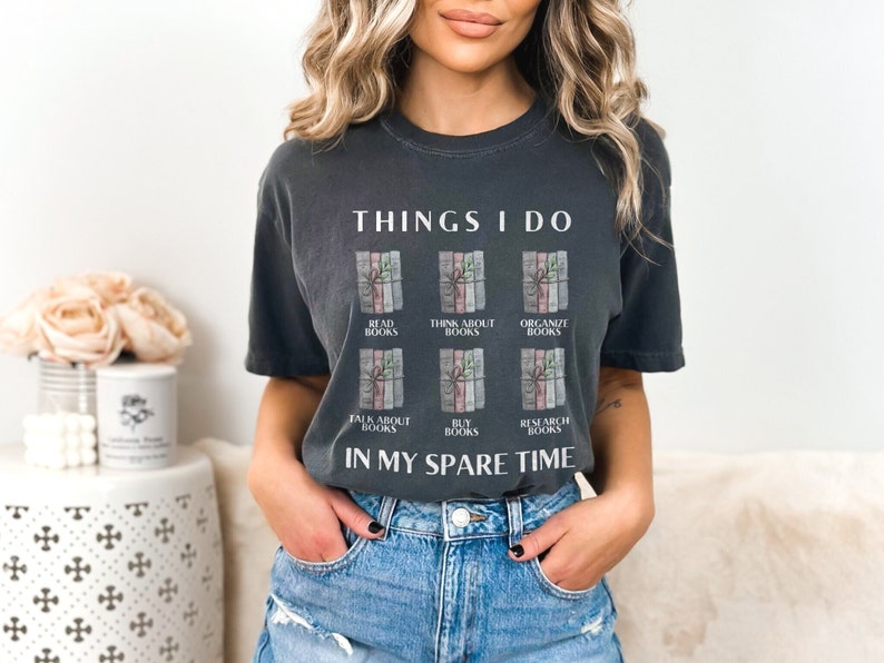 Może przedstawiać: Szary t-shirt z napisem "THINGS I DO" i grafiką sześciu ułożonych książek z r&oacute;żnym tekstem na każdej książce. Tekst na książkach brzmi: "READ BOOKS", "THINK ABOUT BOOKS", "ORGANIZE BOOKS", "TALK ABOUT BOOKS", "BUY BOOKS" i "RESEARCH BOOKS". Tekst "IN MY SPARE TIME" znajduje się pod grafiką.