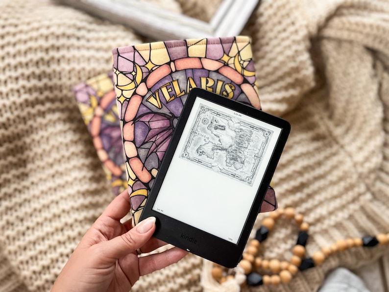 May include: A black Kindle e-reader with a stained glass pattern cover featuring the words "Velaris". The e-reader is displaying a map of the fictional land of Westeros.