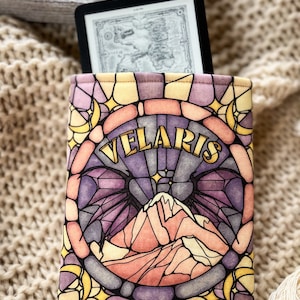 May include: A yellow, purple, and pink stained glass pattern e-reader cover with the word "Velaris" in gold lettering. The design features a mountain range and a crescent moon.