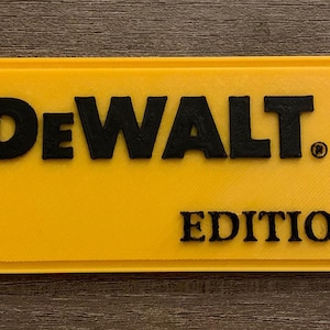 May include: A yellow rectangular sign with the black text "DeWALT" above "EDITION". The sign has a black border and rounded corners. The DeWALT logo is also visible.