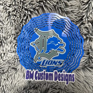 May include: A blue and gray metal wind chime with the Detroit Lions logo and the text "BM Custom Designs".