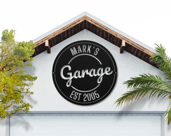 May include: Black metal sign with white lettering that reads "Mark's Garage Est 2005".