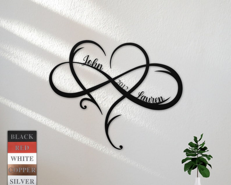 May include: Black metal infinity symbol with a heart in the center. The names "John" and "Lauren" are inscribed on the symbol, along with the year "2012".