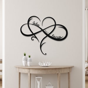 May include: Black metal infinity symbol wall art with a heart in the center. The names "John" and "Lauren" are written on either side of the heart, with the year "2012" written above the heart.