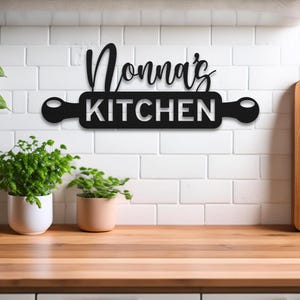 May include: Black metal kitchen sign with the text "Donna's Kitchen" on a rolling pin shape.