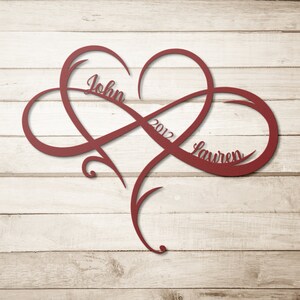 May include: Red metal infinity symbol with a heart in the center. The names "John" and "Lauren" are inscribed on the symbol, along with the year "2012".