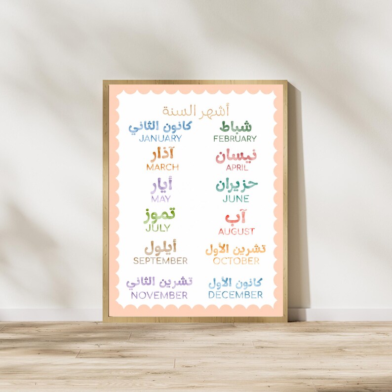 May include: A rectangular wall print featuring a scalloped peach border and a white background. The text displays the twelve months of the year in both Arabic and English, with each month name presented in a unique, colorful watercolor-style font.