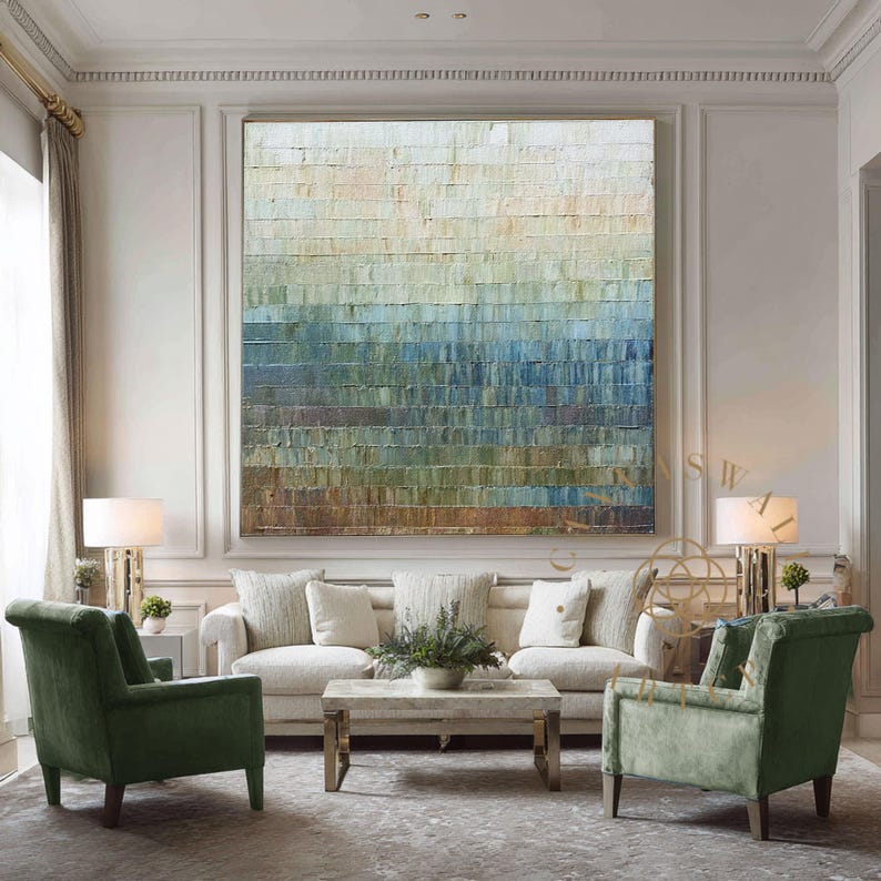 May include: Large abstract painting with a textured surface, featuring horizontal bands of color ranging from white to brown, with shades of blue and green. The artwork hangs above a cream-colored sofa, flanked by green armchairs.