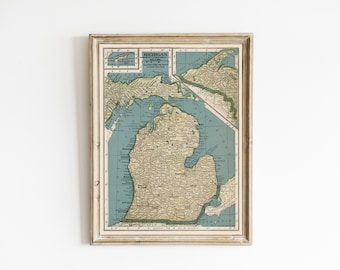 May include: A framed vintage map of Michigan with a blue and green color scheme. The map shows the state's borders, major cities, and rivers. The frame is a light wood color.