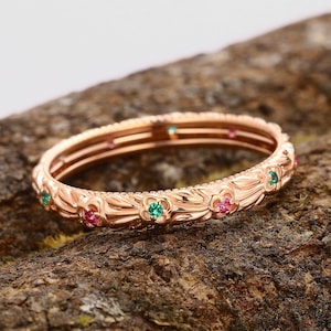 Peut inclure: Une bague en or rose avec un motif floral délicat et de petites pierres précieuses vertes et roses.