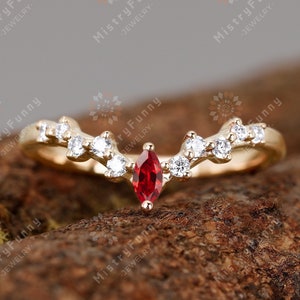 Peut inclure: Une bague en or avec une pierre précieuse rouge et de petites pierres précieuses blanches serties dans un délicat motif de vigne.