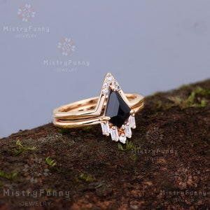 May include: A gold ring set with a black gemstone and smaller white gemstones. The ring is set on a wooden surface.