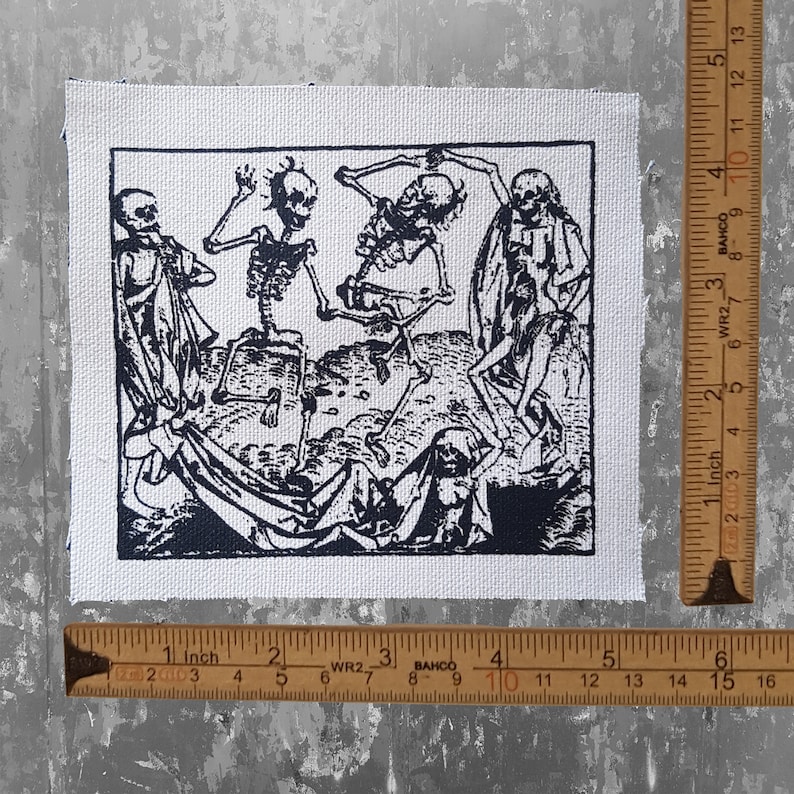 May include: Black and white print of a vintage woodcut depicting a group of skeletons dancing. The skeletons are dressed in robes and are holding hands. The print is on a white canvas background.