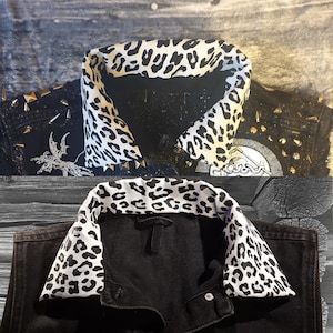 May include: Black denim jacket with a black and white leopard print collar. The jacket has silver studs and a patch on the back.