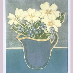 May include: A blue ceramic jug with a gold rim filled with yellow primroses and blue forget-me-nots.