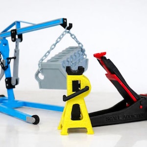 Peut inclure: Un ensemble de réparation automobile miniature comprenant un pont roulant bleu, un chandelle jaune et un cric de sol noir avec des accents rouges. Un bloc moteur gris est suspendu au pont roulant. Le cric de sol porte le texte "SCALE ADDICTION".