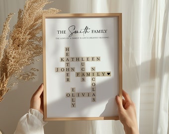 May include: A framed print with the text "The Smith Family" and a crossword puzzle design featuring family names. The print includes the phrase "The love of a family is life's greatest blessing" and is displayed in a light-colored wooden frame.