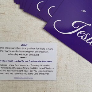 Jesus gospel tract – Acts 4:12 scripture card with salvation prayer on back; purple “Jesus” fronts in fan spread on linen background; Christian evangelism witnessing cards by God’s Creation Tracts, 25–250 pack options