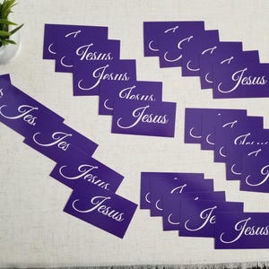 Jesus gospel tracts — Acts 4:12 Christian scripture cards with salvation prayer; multiple purple “Jesus” fronts scattered on linen surface with small plant décor; 25-pack (25–250 options).