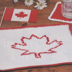 Può includere: Sottobicchiere in crochet bianco con un design a foglia d'acero canadese in crochet rosso. Il sottobicchiere ha un bordo rosso.