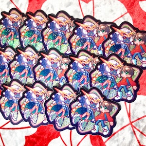 May include: A stack of colorful stickers featuring a cartoon character with three eyes and a human-like figure. The character is wearing a blue and white striped outfit with a red and white striped stocking. The human-like figure is wearing a red shirt and blue jeans.