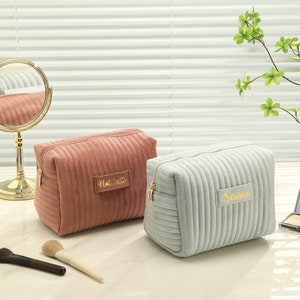 three cosmetic bags sitting on a table next to a mirror