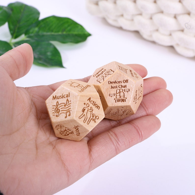 a hand holding two wooden dices with writing on them