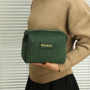 a woman holding a green purse with a name on it