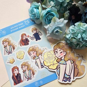 以下が含まれることがあります： 「Golden Rose Sticker Sheet」というテキストと、人々や花を描いたイラストが描かれたステッカーシート。シートは青い花が咲いた白い背景の上に置かれている。