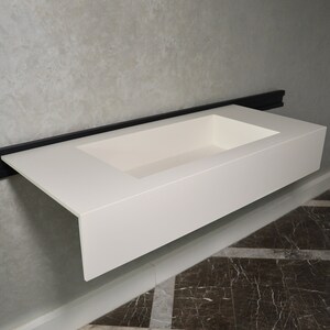 May include: White rectangular countertop sink with a built-in basin. The sink is mounted to a wall with a black metal bracket.