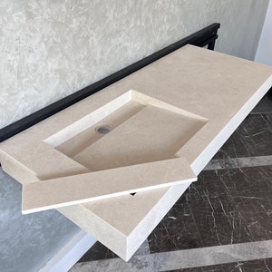 May include: A white rectangular bathroom sink with a single hole for a faucet. The sink is mounted on a black metal frame and has a white countertop.