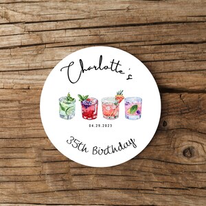 May include: White round sticker with the text "Charlotte's 35th Birthday" and the date "04.29.2023". Four colorful cocktail illustrations are arranged horizontally in the center of the sticker.