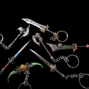 Puede incluir: Colección de llaveros de armas de fantasía en miniatura, que incluyen espadas, hachas y una guadaña. Los llaveros presentan detalles intrincados con acentos metálicos plateados, dorados, azules, verdes y marrones. Cada llavero tiene un anillo de metal.
